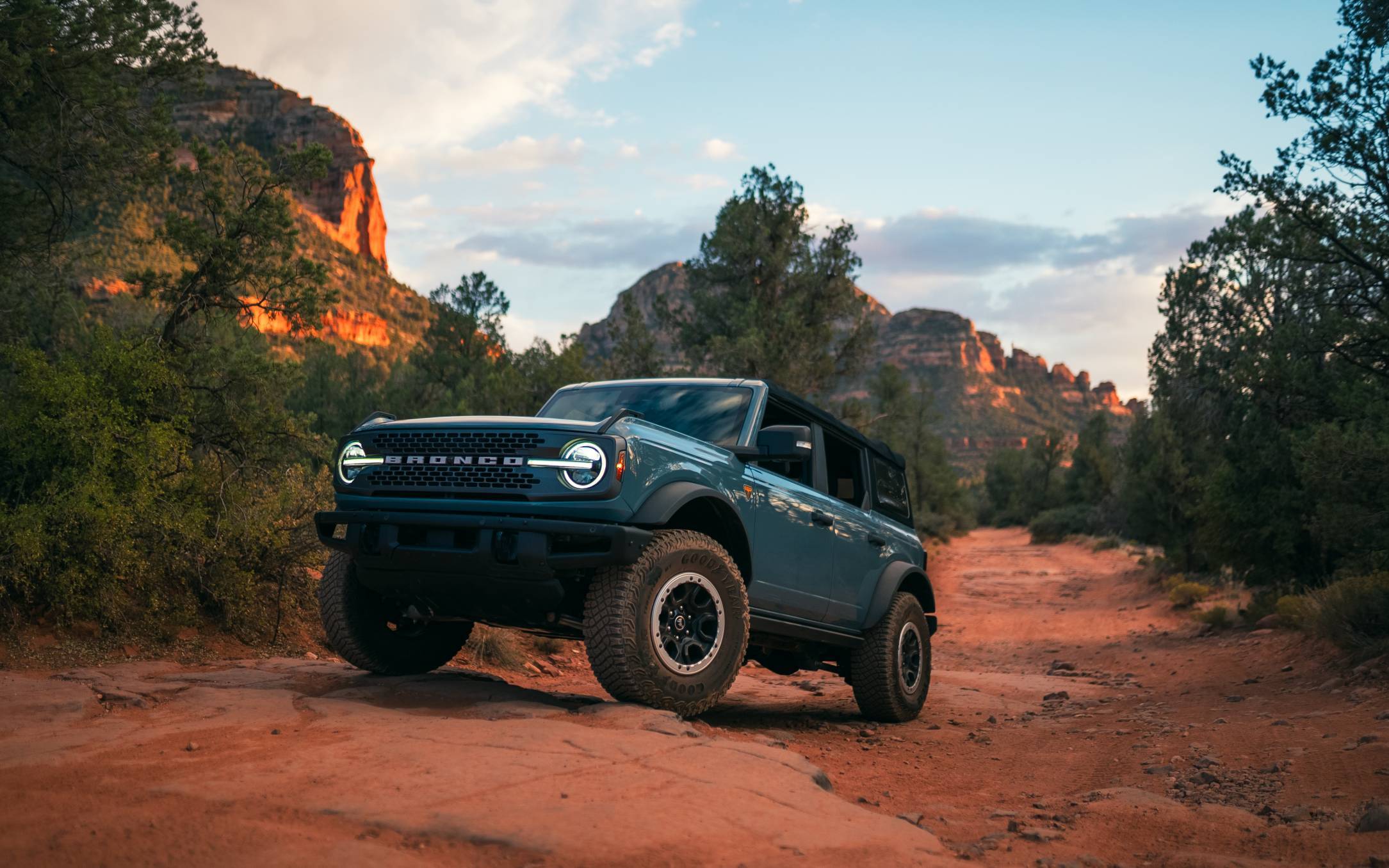 A blue Ford Bronco driving over some off-road terrain.